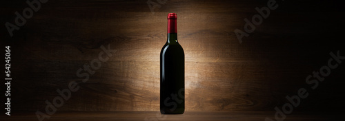 green bottle with red wine on a wood panorama background