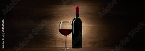 green bottle with red wine and glass on a wood panorama