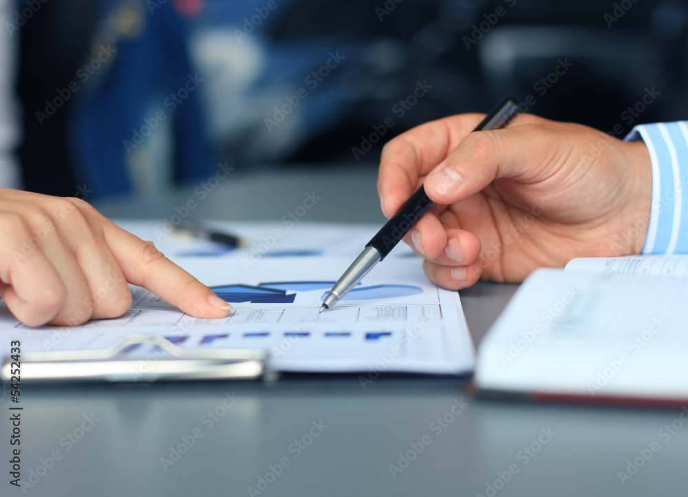 Unrecognizable business person analyzing graphs and taking notes Unrecognizable business person analyzing graphs and taking notes