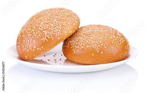 Two round sandwich bun with sesame seeds on a plate isolated