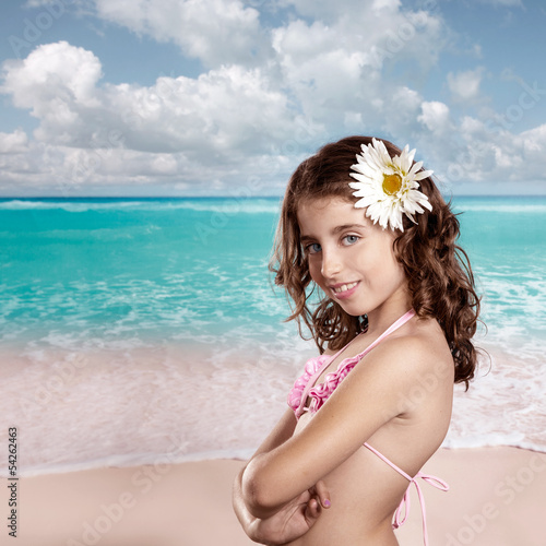 Brunette girl in tropical beach with daisy flower happy