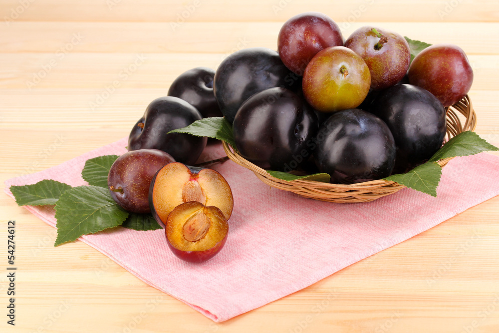 Rip plums on basket on wooden table Rip plums on basket on wooden table
