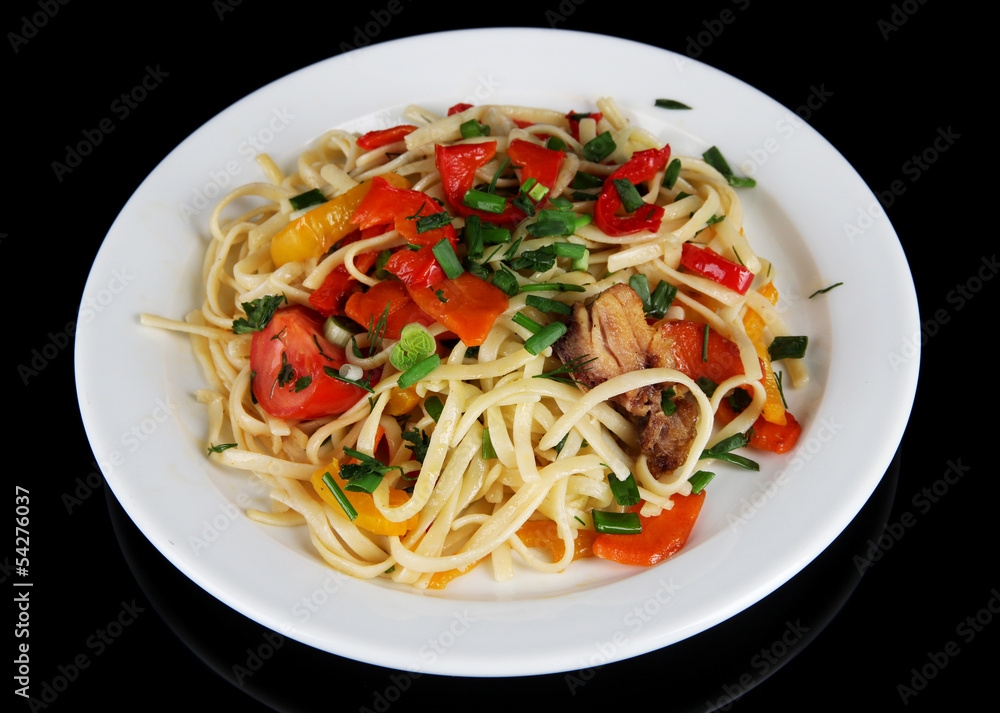 Noodles with vegetables on plate isolated on black