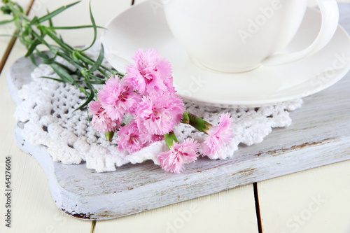 Many small pink cloves in cup on wooden board close-up