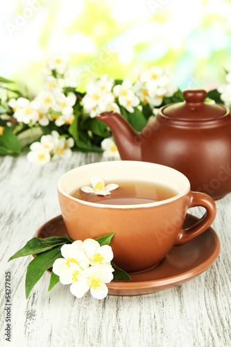 Cup of tea with jasmine, on wooden table, on bright background