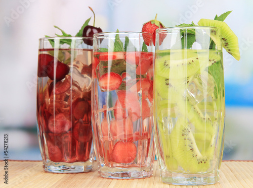 Glasses of fruit drinks with ice cubes on table in cafe