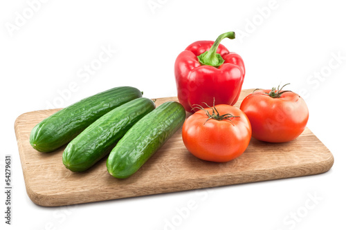 cucumbers, tomatoes and peppers on wooden board