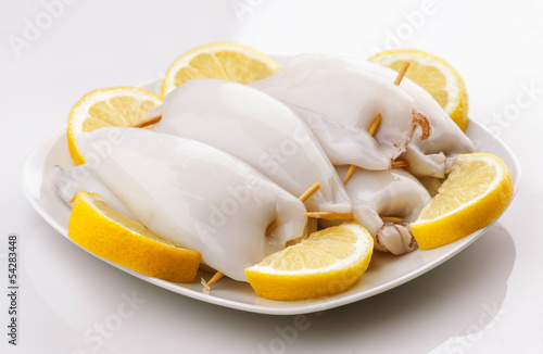 raw squid stuffed ready to be cooked in plate and cut lemons