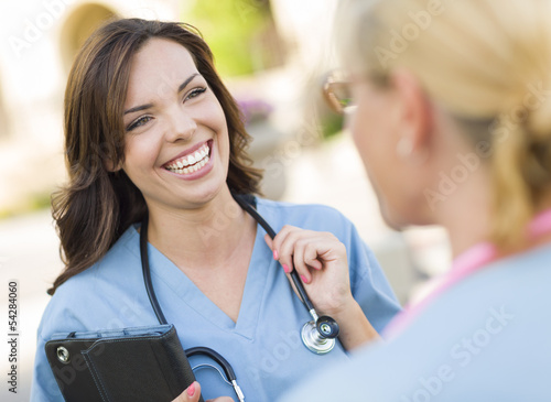 Two Young Adult Female Doctors or Nuses Talking Outside