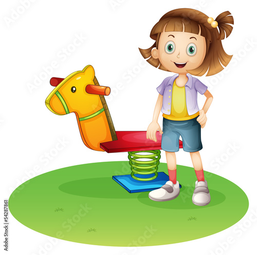 A girl standing beside a horse spring toy