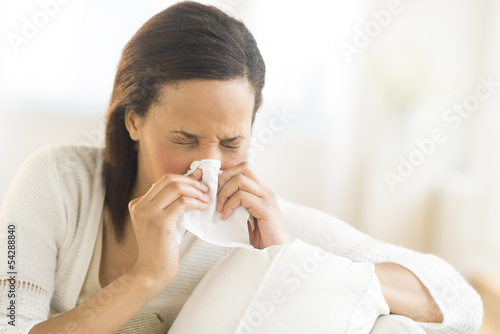 Woman Blowing Nose With Tissue At Home
