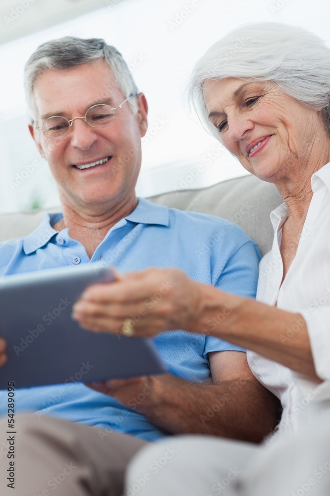 Obraz premium Couple using a digital tablet sitting on the couch