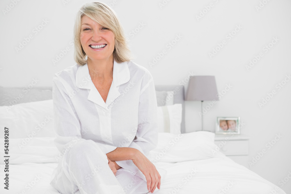 Happy woman sitting cross legged  in her bedroom