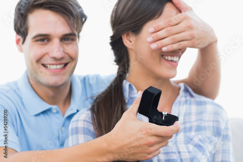 Man hiding his girlfriend eyes and offering her an engagement ri