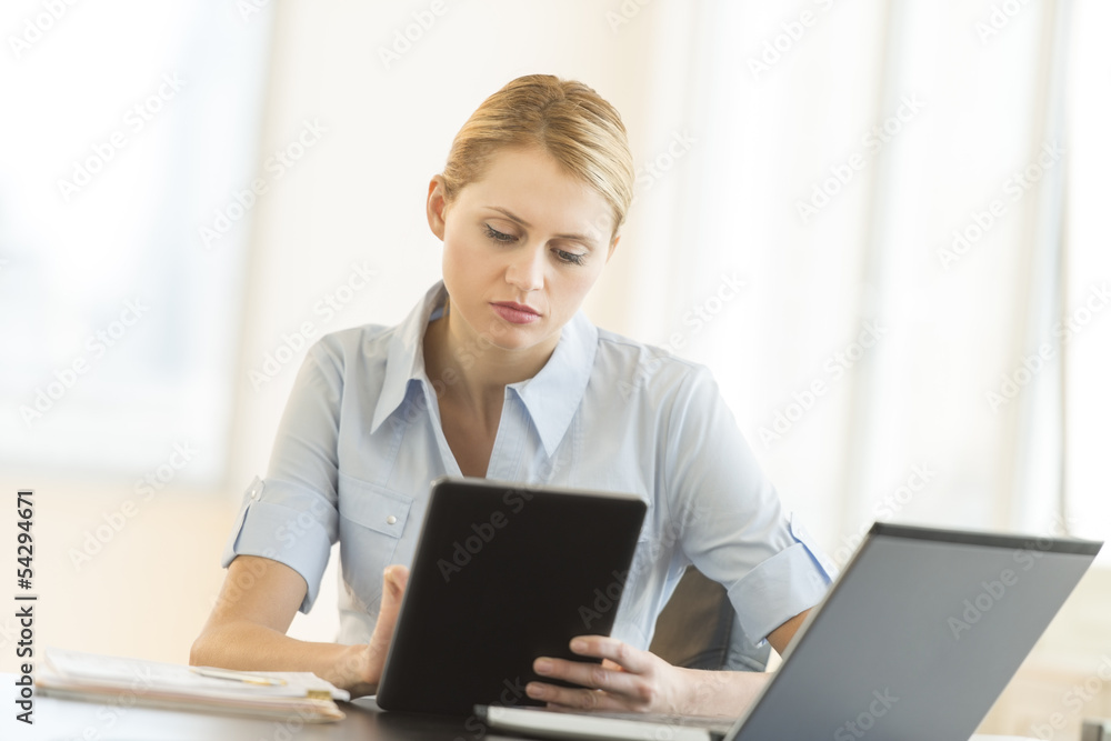 Businesswoman Using Digital Tablet While Sitting At Desk Businesswoman Using Digital Tablet While Sitting At Desk