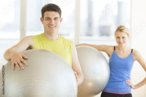 Man And Woman With Pilates Smiling In Health Club