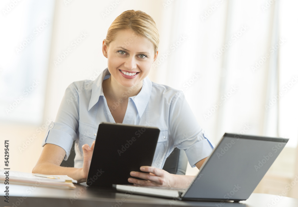 Businesswoman With Digital Tablet And Laptop Sitting At Desk Businesswoman With Digital Tablet And Laptop Sitting At Desk