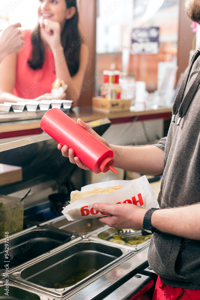Hotdog being diligently prepared by fast food chef Hotdog being diligently prepared by fast food chef