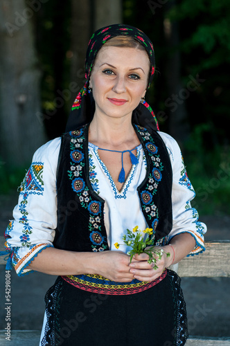 beautiful singer with flowers in her hands posing at countryside