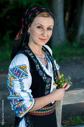 beautiful singer with flowers in her hands posing at countryside