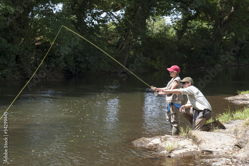 Fly fishing gillie instructing a pupil River Lyd Devon UK