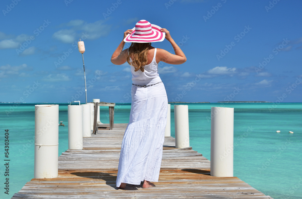 Girl on the wooden jetty looking to the ocean. Exuma, Bahamas