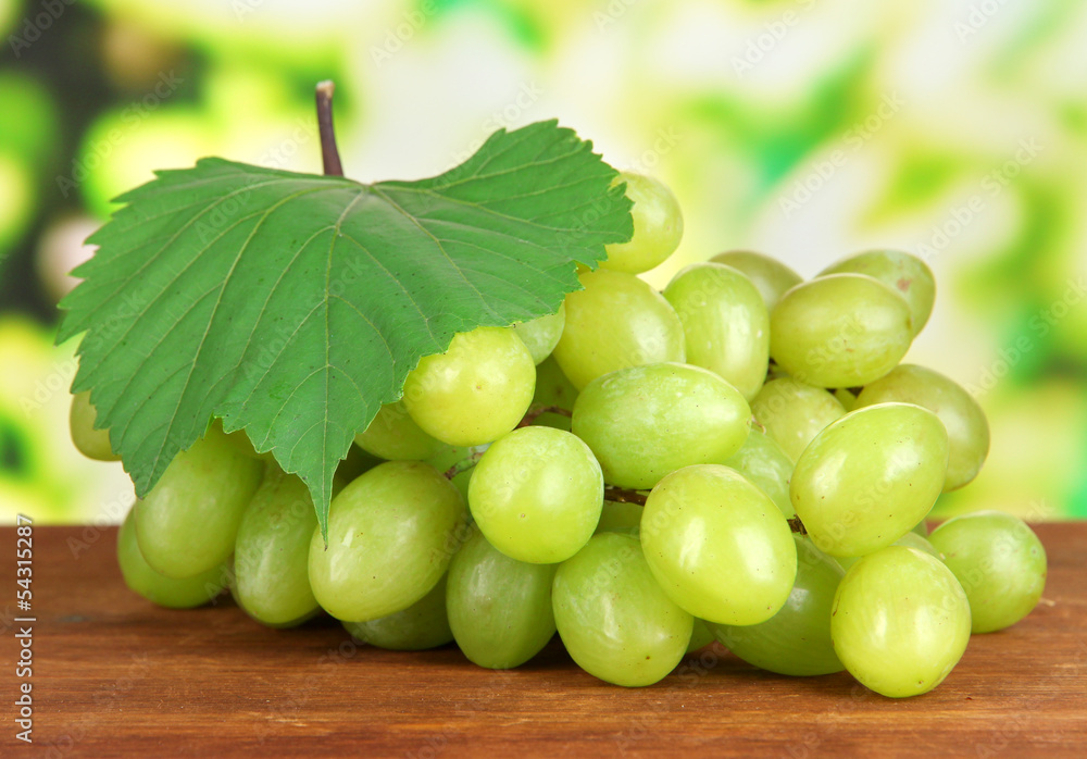 Ripe delicious grapes on table on bright background Ripe delicious grapes on table on bright background