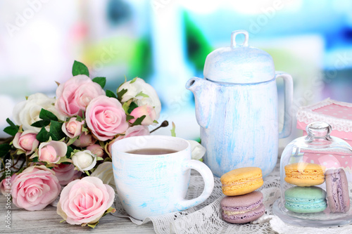 Macaroons in bowl on wooden table on room background