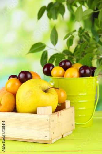 Bright summer fruits in pail and wooden box