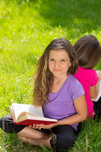 Zwei Mädchen beim Buch lesen auf der Wiese