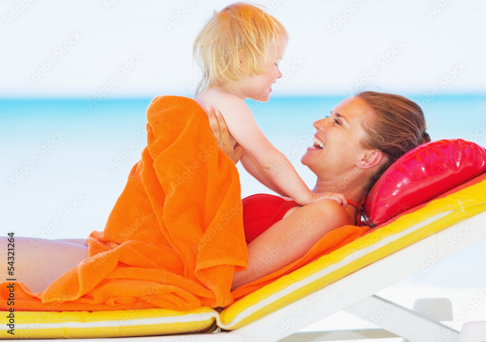 Happy mother and baby laying on sunbed