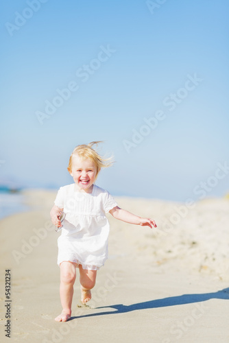Happy baby running on beach
