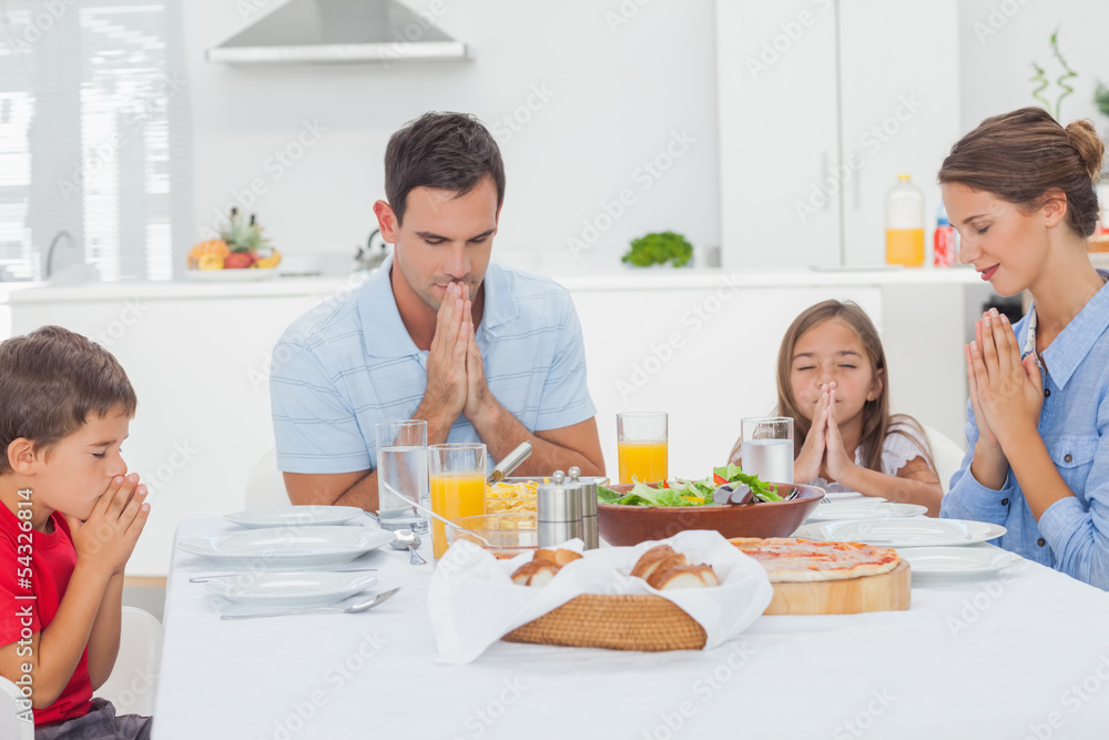 Family saying grace before dinner