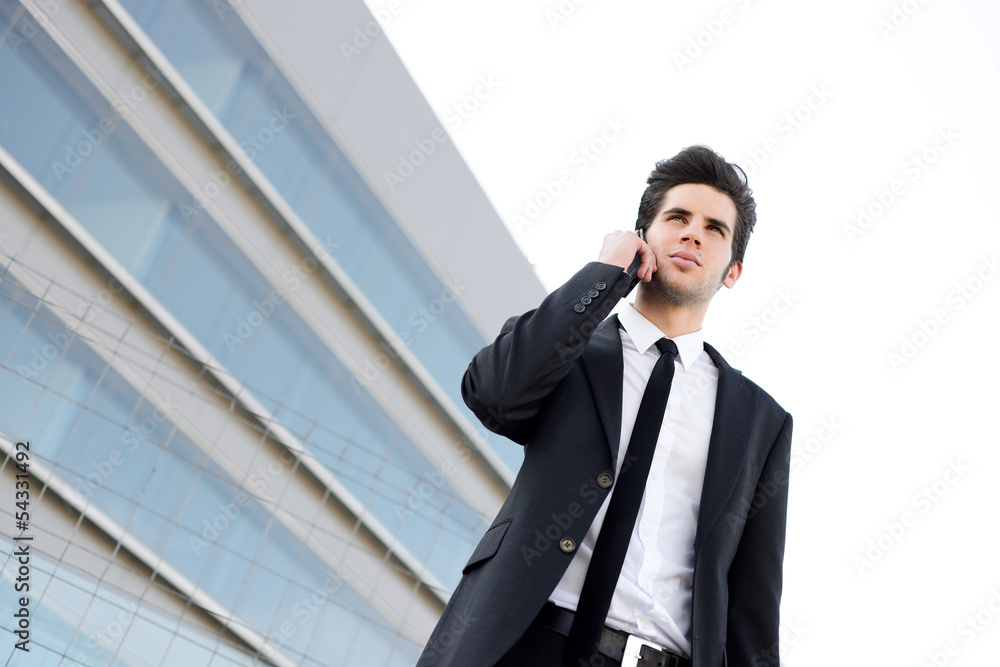 Attractive young businessman on the phone in an office building Attractive young businessman on the phone in an office building