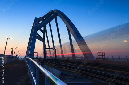 Train speeding over a bridge at dusk.