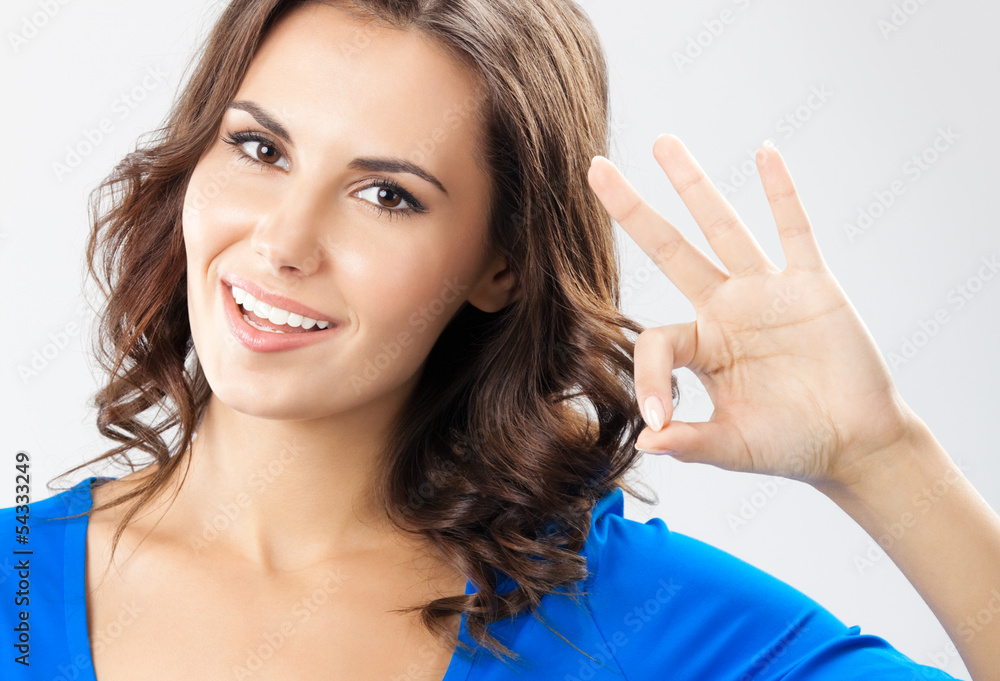Young woman showing okay gesture, over grey Young woman showing okay gesture, over grey
