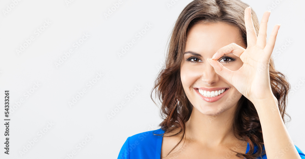 Young woman showing okay gesture, over grey Young woman showing okay gesture, over grey