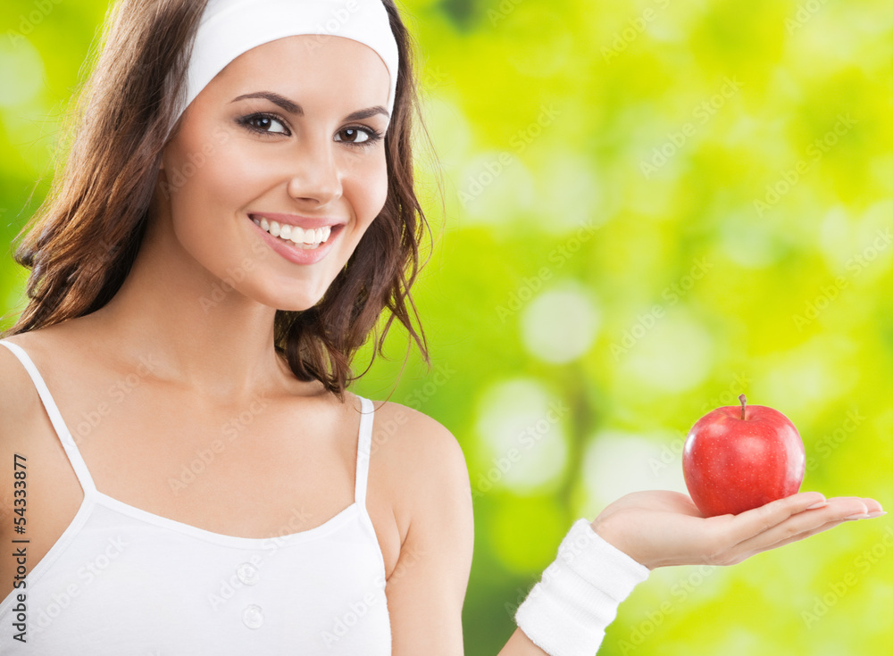 Woman in fitness wear with apple, outdoors Woman in fitness wear with apple, outdoors