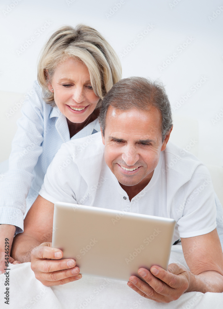 Happy Mature Couple Looking At Digital Tablet Happy Mature Couple Looking At Digital Tablet