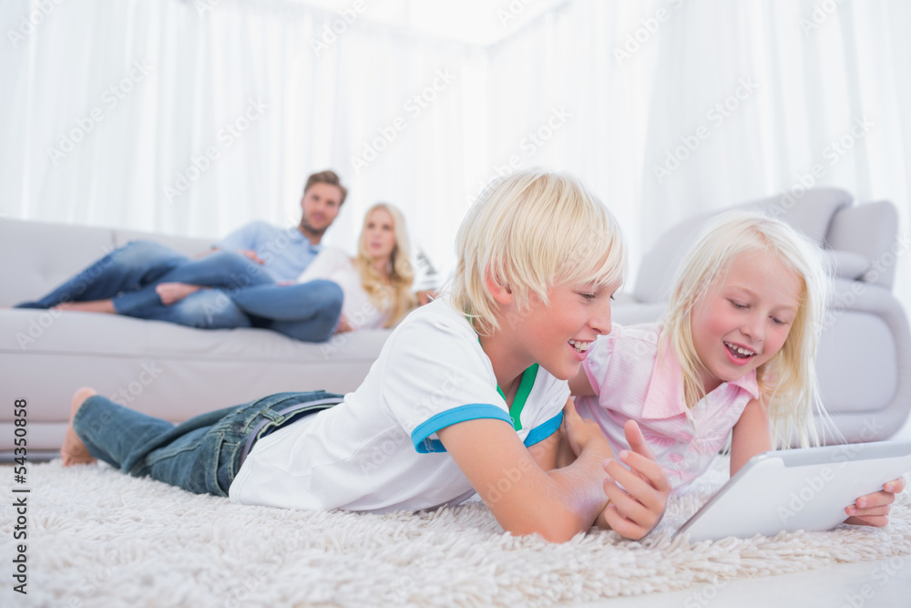 Children lying on the carpet using digital tablet