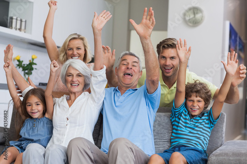 Multi-generation family raising their arms