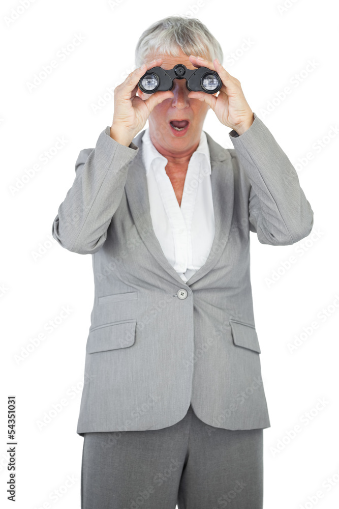 Astonished businesswoman looking at something through binoculars Astonished businesswoman looking at something through binoculars