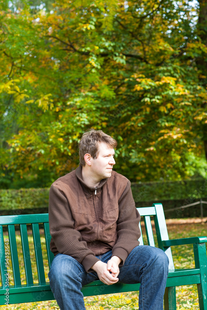 young man in the autumn park sitting on bench young man in the autumn park sitting on bench