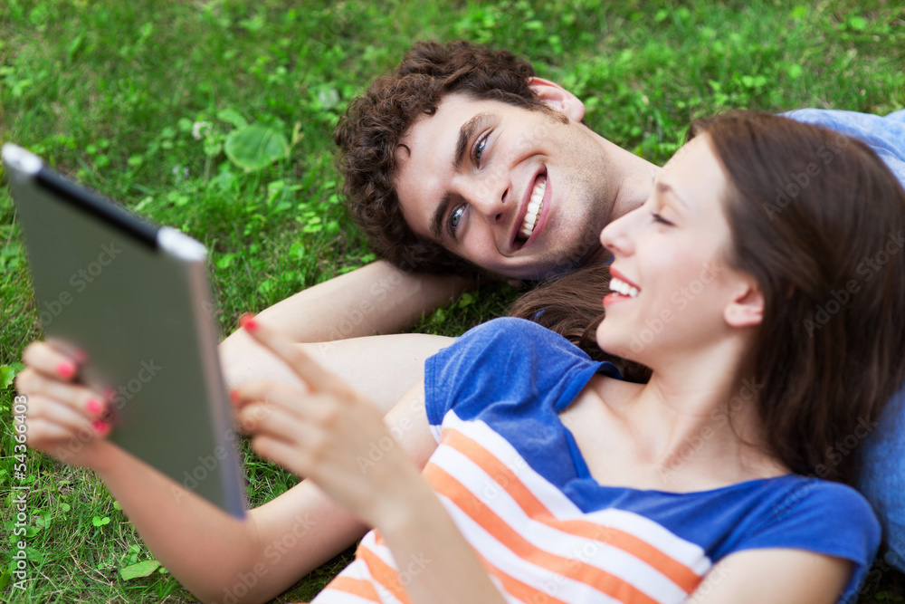 Couple using digital tablet on lawn Couple using digital tablet on lawn