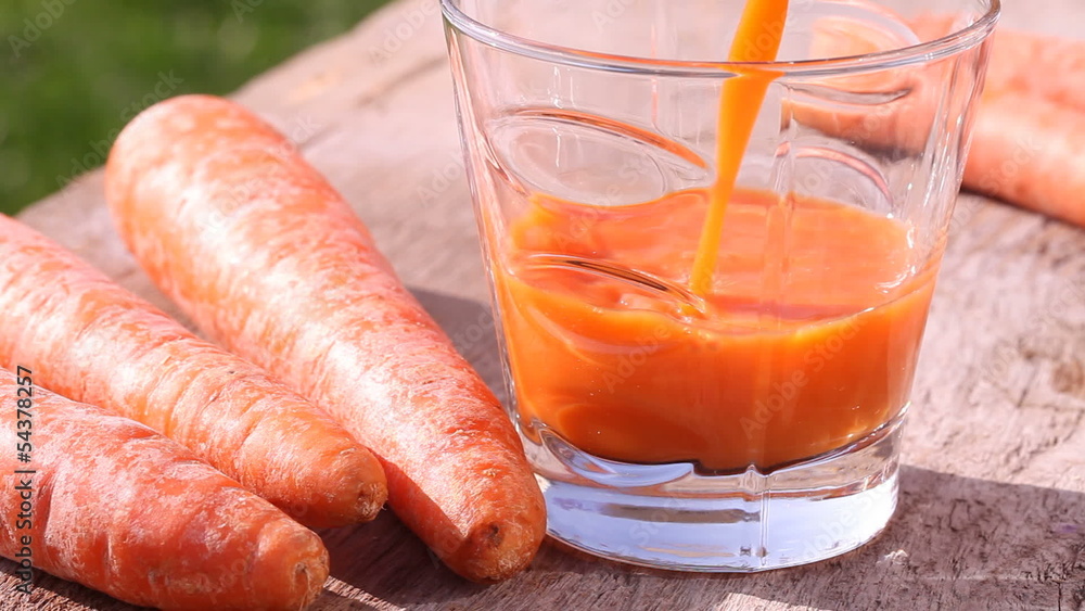 Close-up of glass with pouring carrot juice. Close-up of glass with pouring carrot juice.