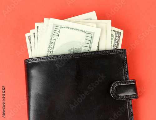 Wallet with hundred dollar banknotes, on color background