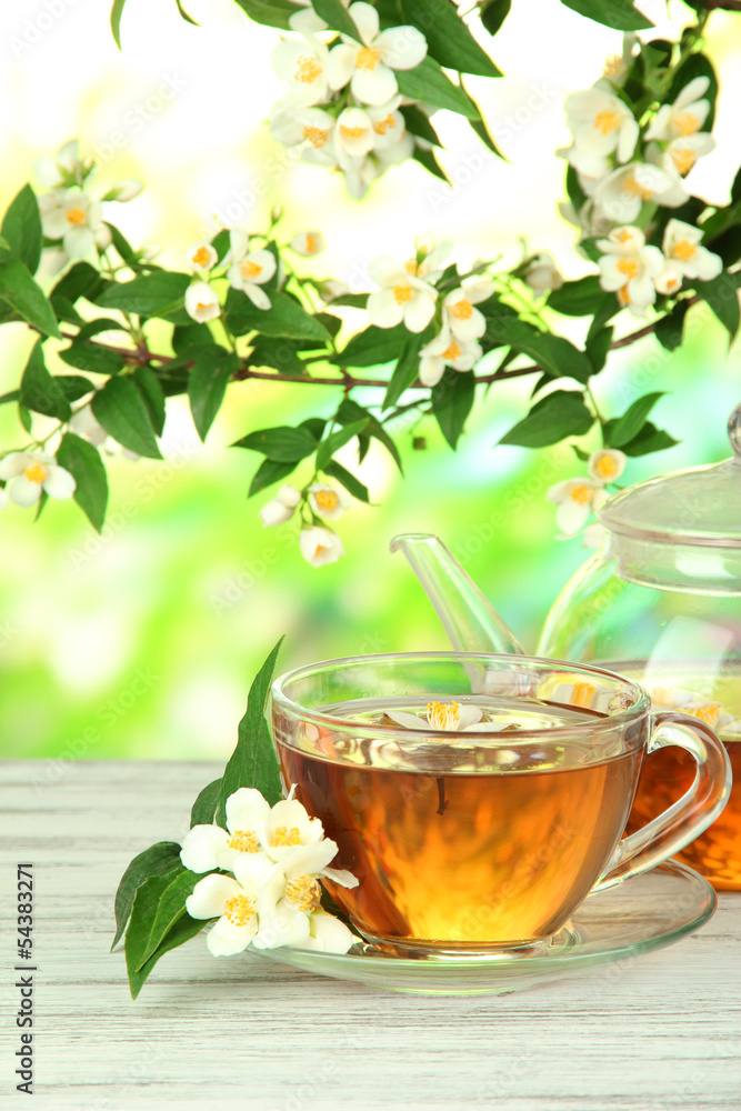 Cup of tea with jasmine, on wooden table, on bright background Cup of tea with jasmine, on wooden table, on bright background