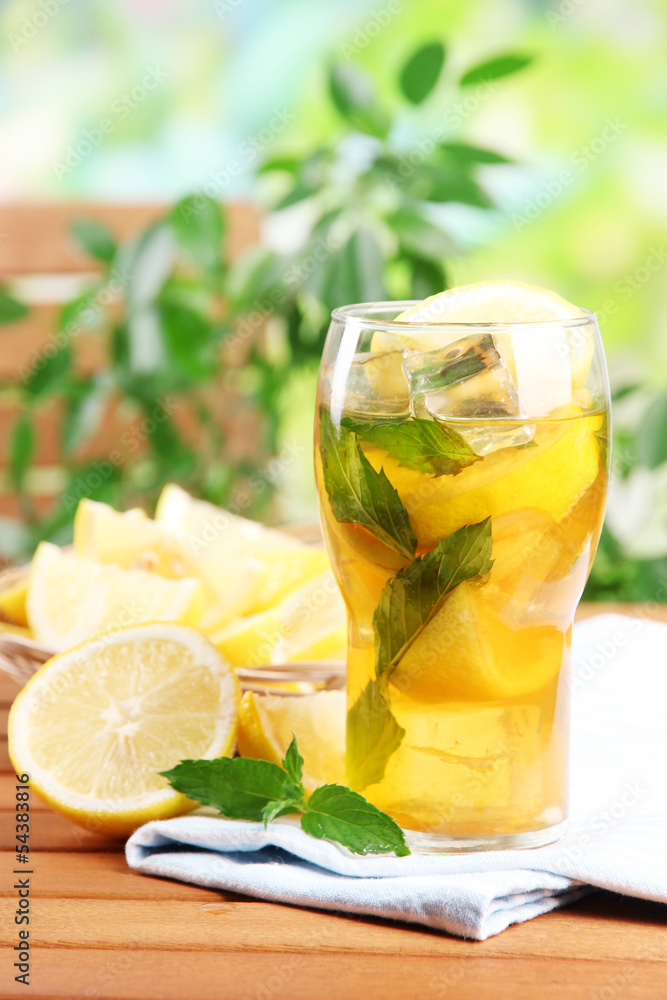Fototapeta premium Iced tea with lemon and mint on wooden table, outdoors