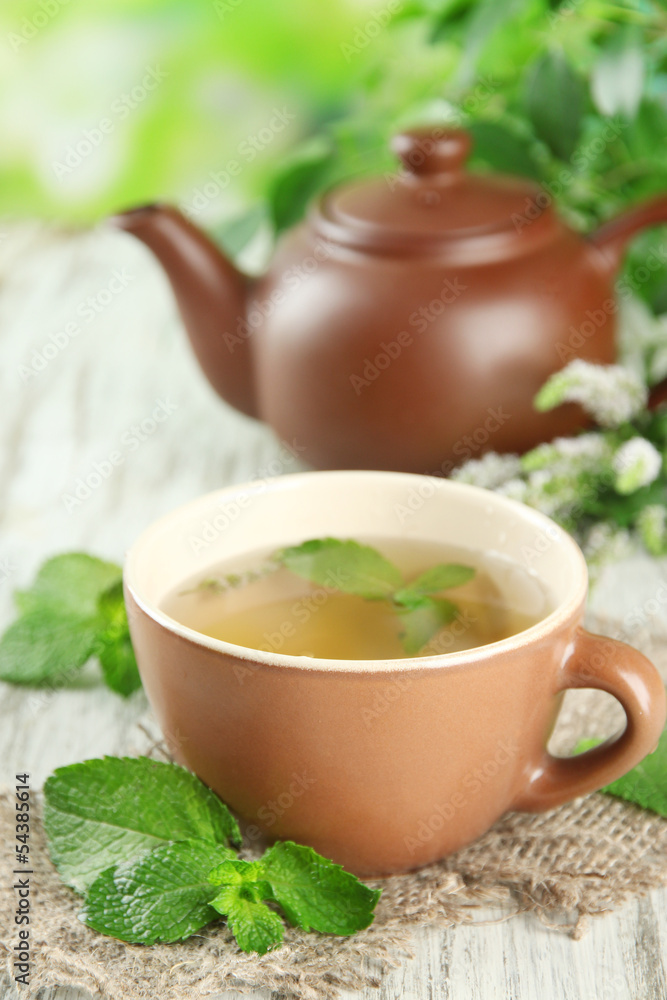 Teapot and cup of herbal tea with fresh mint flowers Teapot and cup of herbal tea with fresh mint flowers