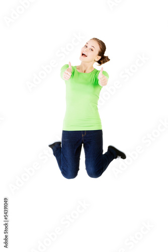 Young happy caucasian woman jumping in the air with thumbs up photo